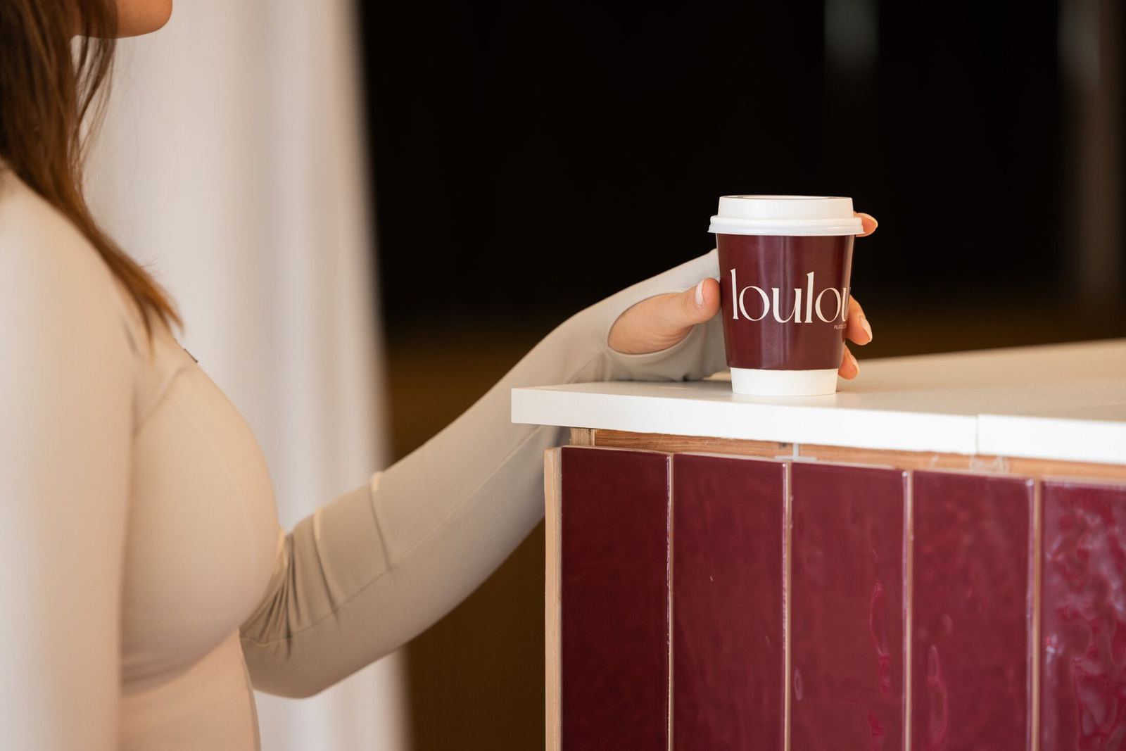 Een Loulou-koffiebeker op de bordeaux tegelbalie