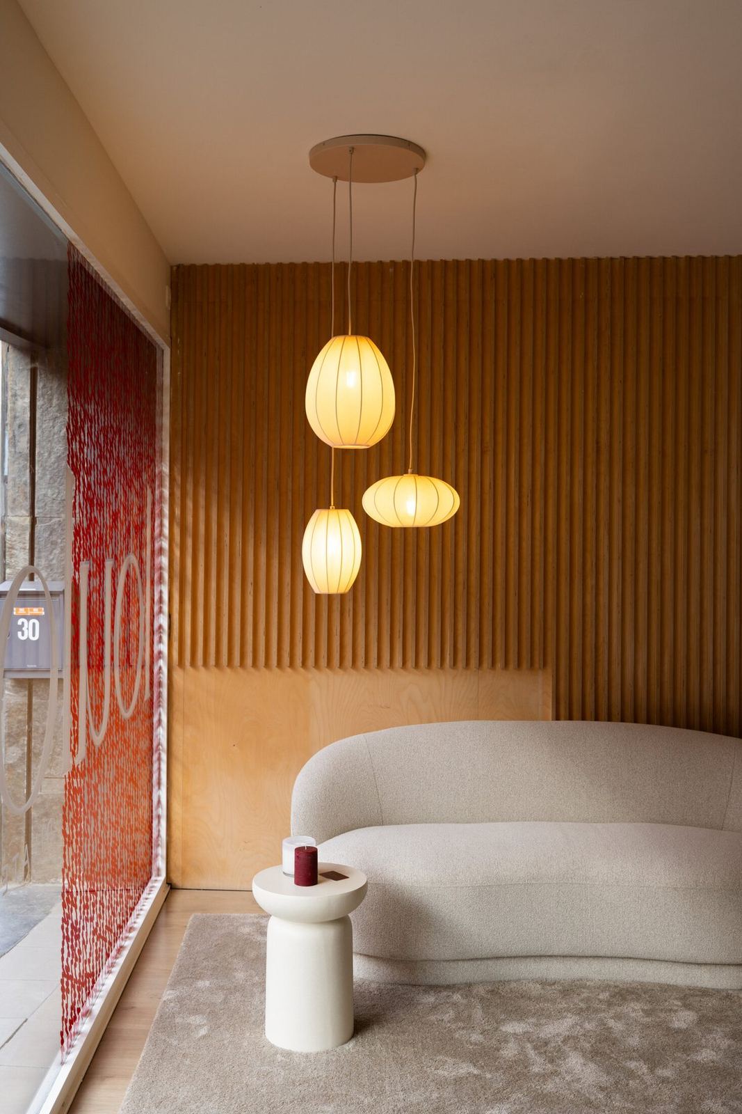 De lounge met ronde zetel, papieren lampen en bordeaux tegelwand