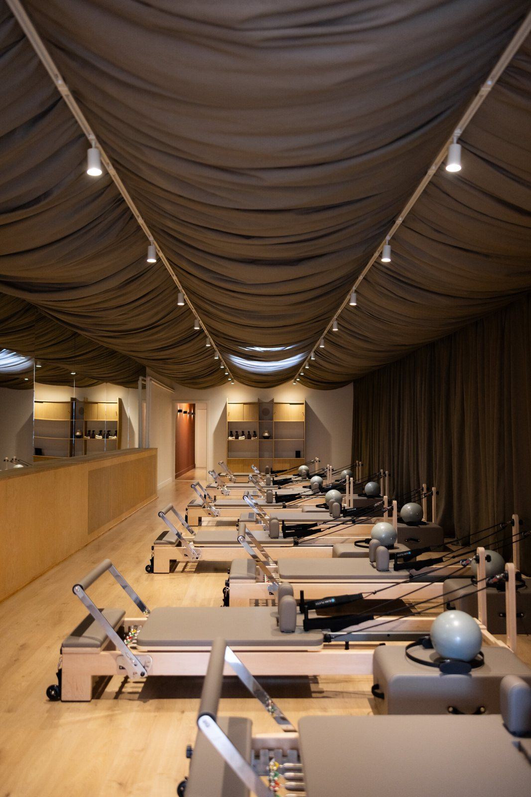 De reformerzaal met warm licht onder de drapes